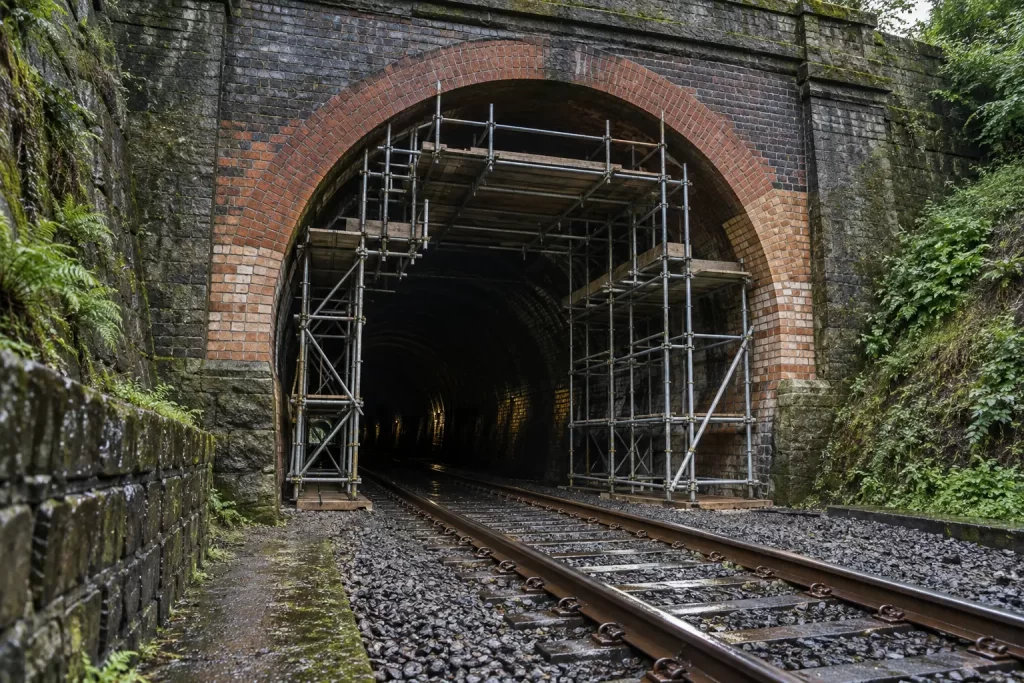 Scaffolding supports the arched entrance of a Victorian brick railway tunnel under restoration.