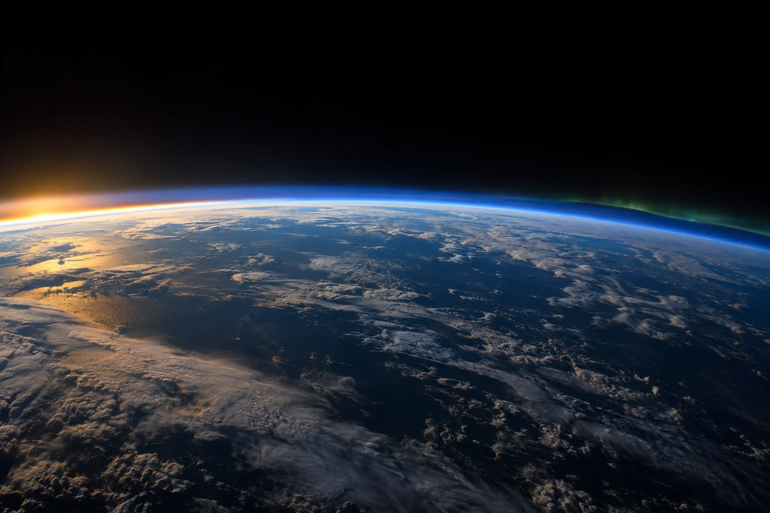 The curved blue atmospheric edge of Earth rises above clouds and ocean with a faint polar glow.