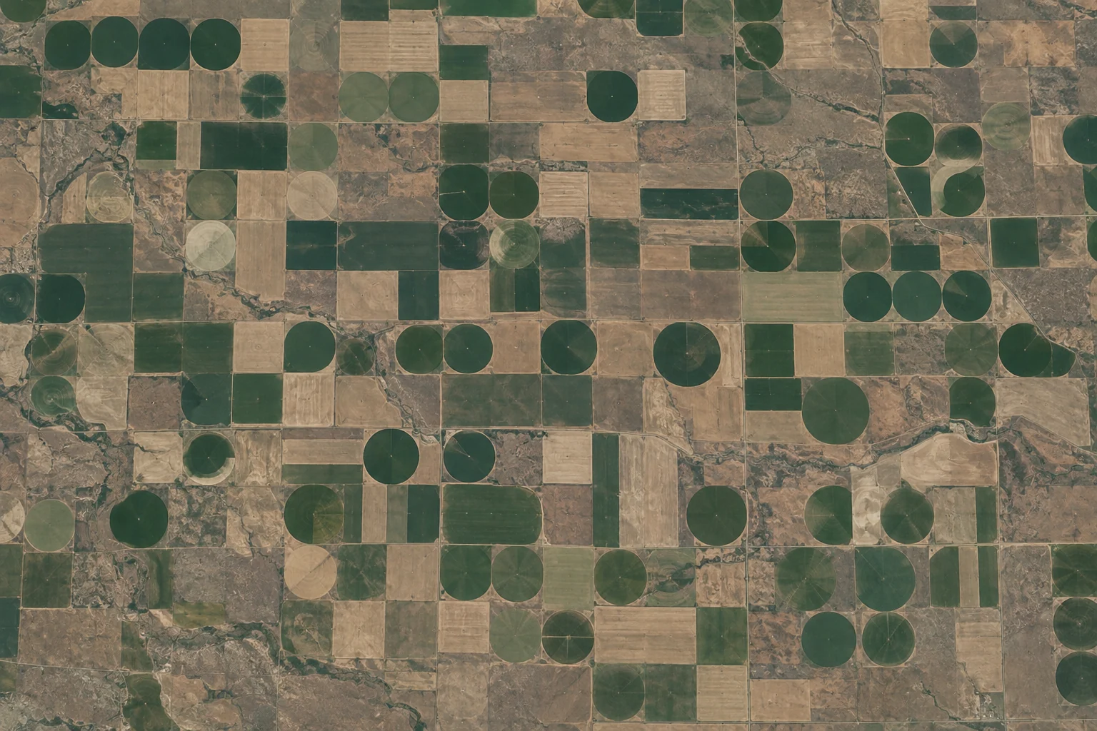 A high orbital view reveals green irrigation circles and pale rectangular fields across Montana farmland.