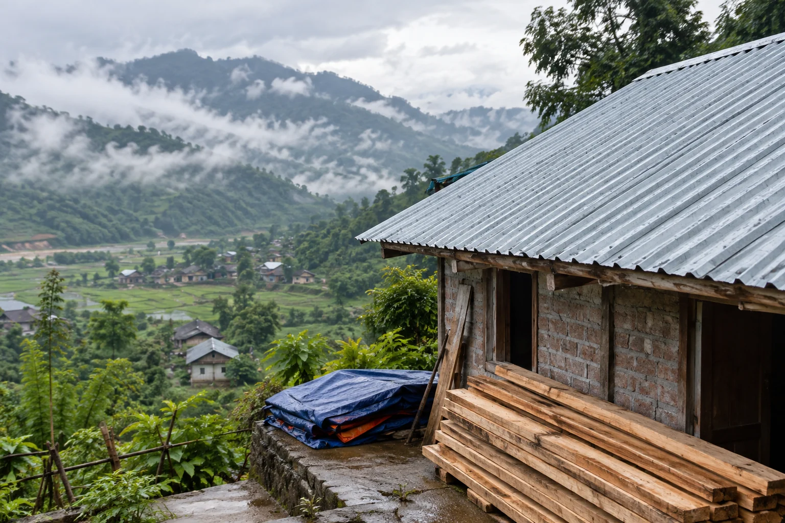 A repaired metal roof and stacked timber stand beside a brick house in a misty mountain valley.